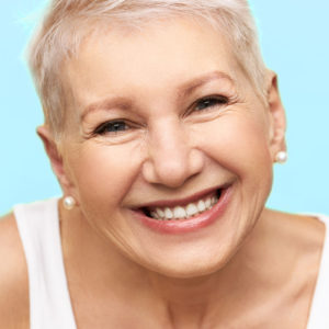 Portrait of good looking cheerful middle aged European female with stylish hairdo wearing white tank, expressing positive emotions, smiling broadly, showing straight teeth, happy to receive good news